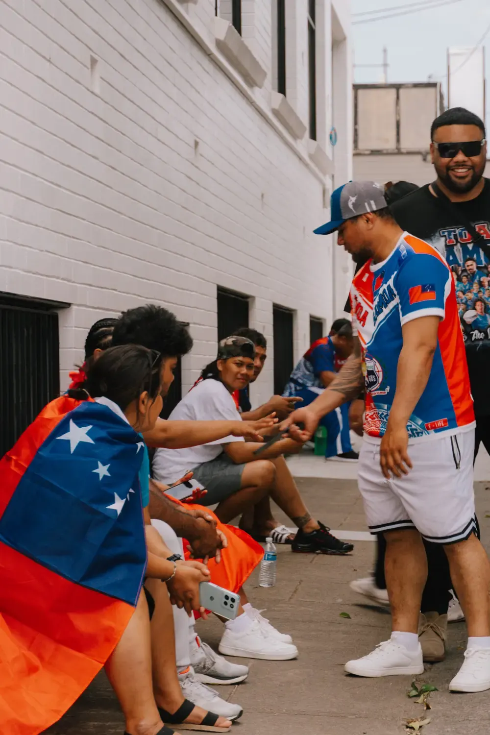 A TRAILS community member greeting families wrapped in the Samoan flag