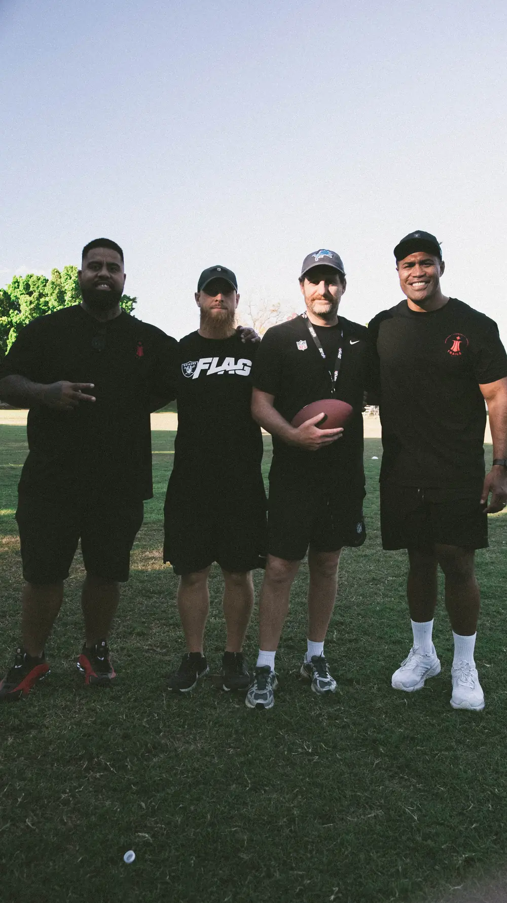 Four TRAILS coaches standing together on the field, one holding a football