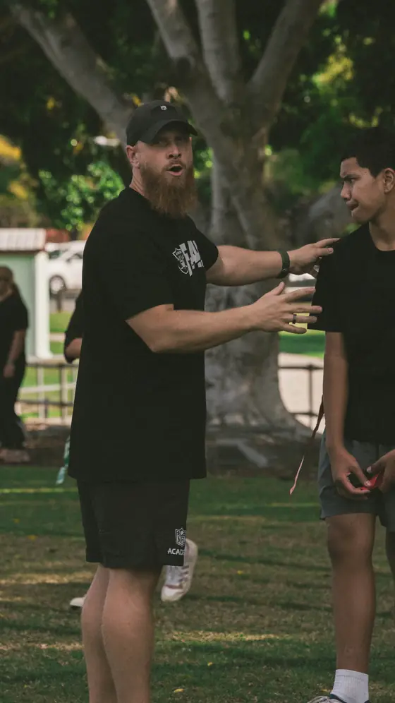 A mentor talking a young person through a drill on the field
